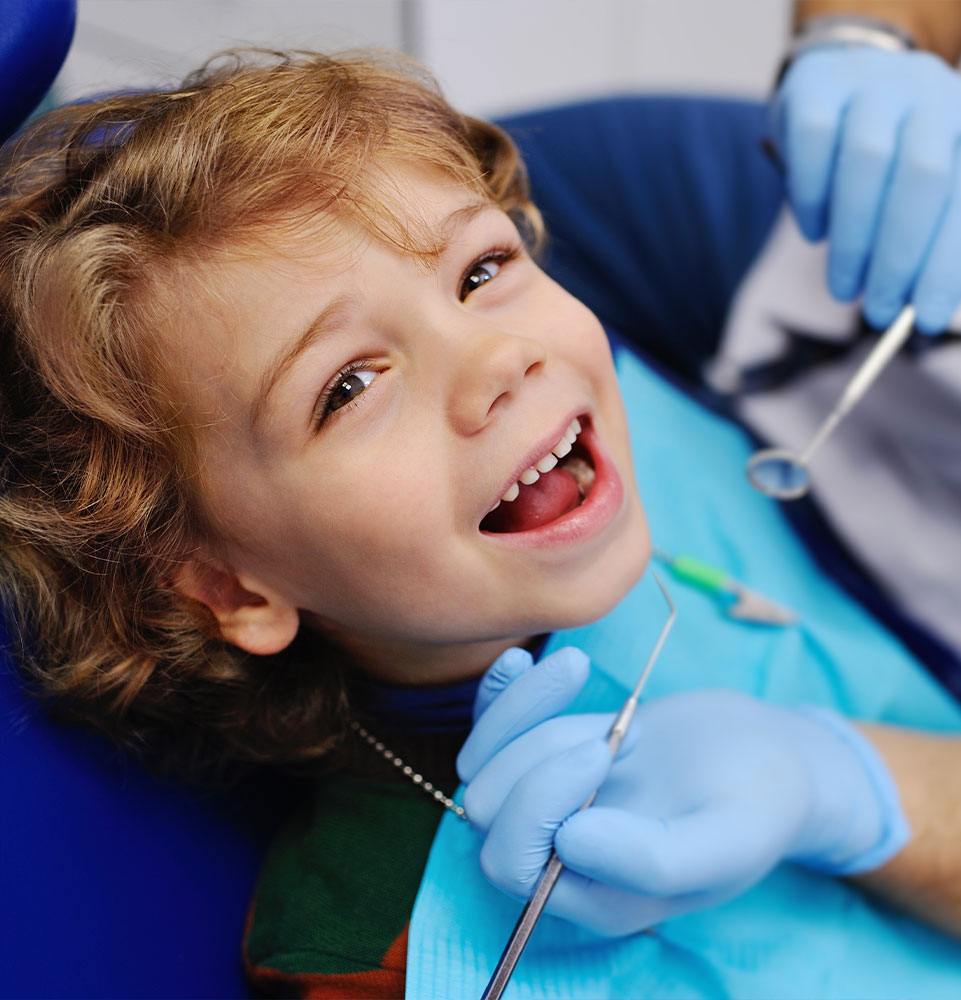 smiling child sitting in a blue chair dental