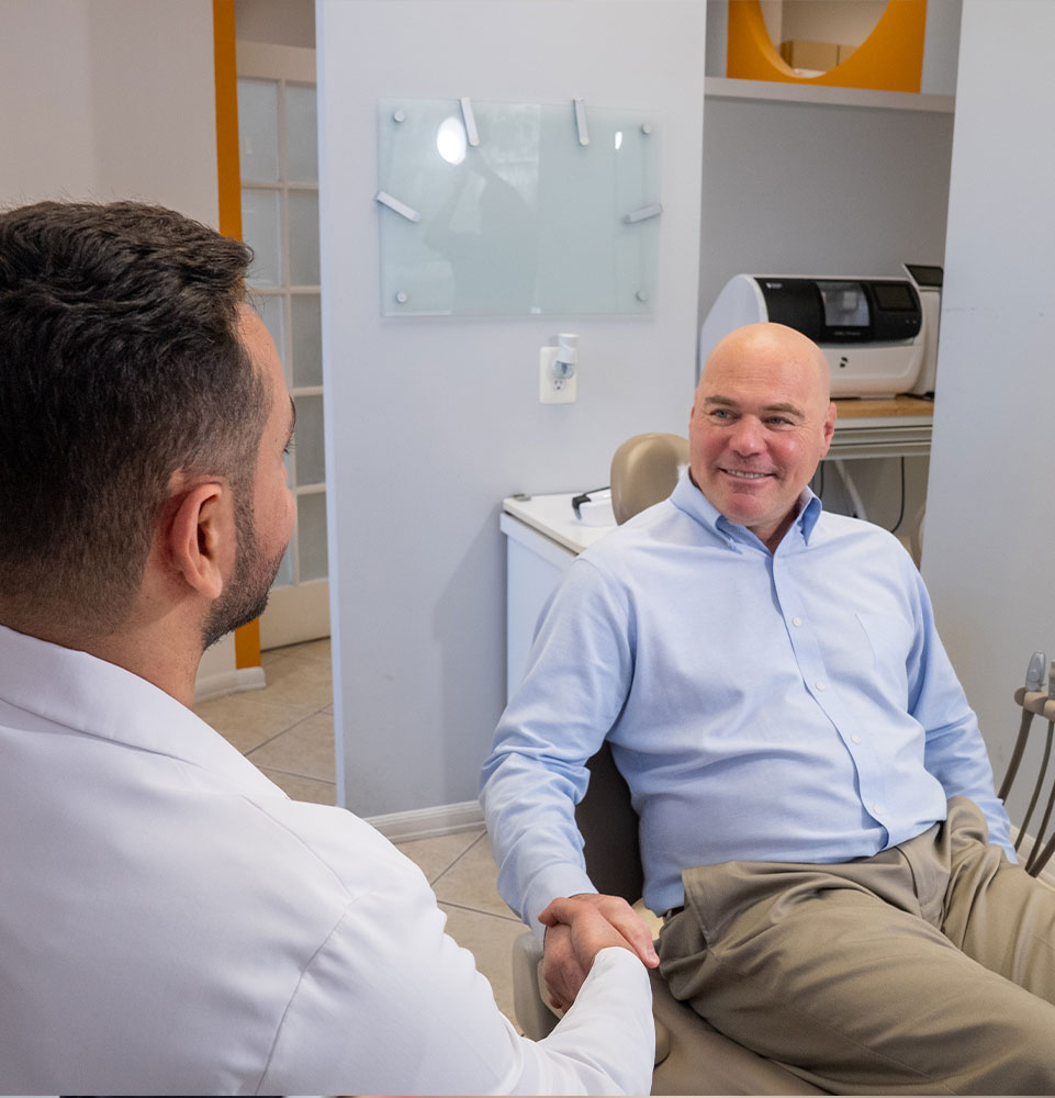 patient shaking hands with doctor and going over dental treatment information