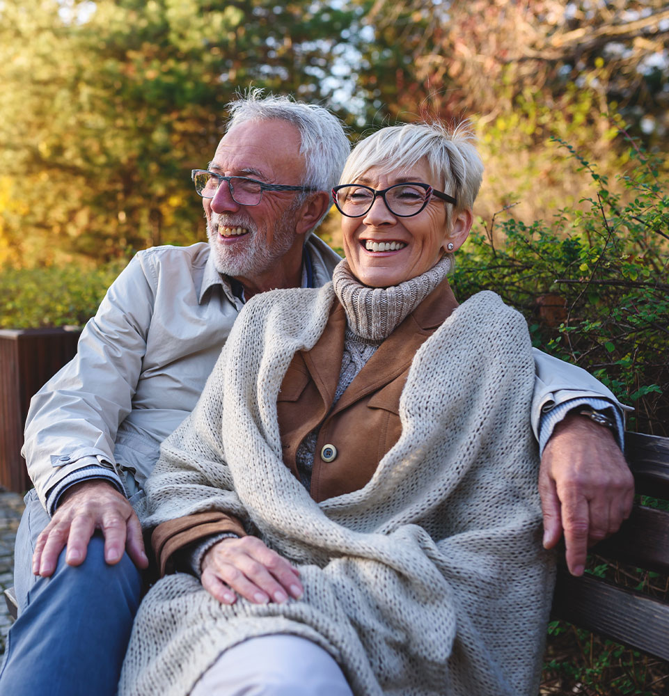Smiling senior couple sitting on the bench in the park together