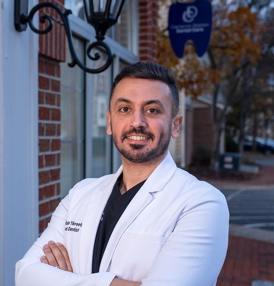 headshot of doctor smiling brightly while outside of the dental center