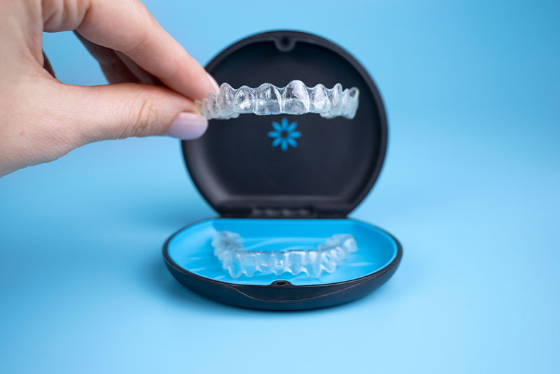 Woman holding invisalign transparent retainers with a box on the table