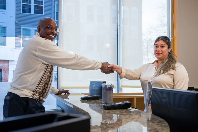 patient shaking hands with staff member at the front desk of the dental center