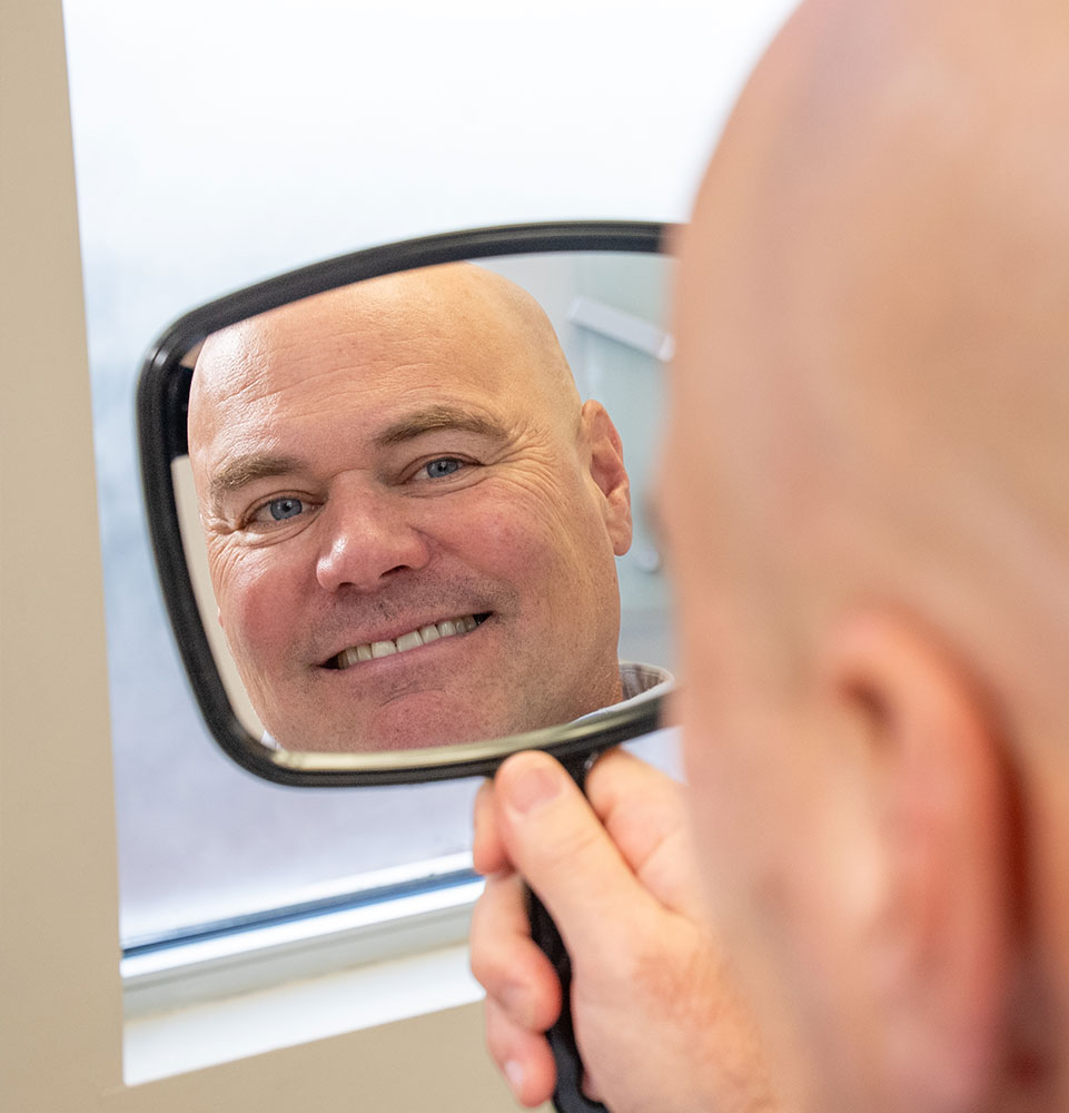 patient smiling bright looking in a mirror after their dental treatment